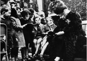 Maria Montessorii wspólnie z dziećmi czyta książkę.